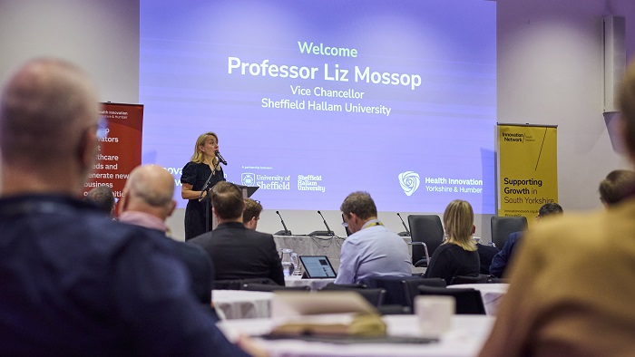 Person speaking at a lectern with people facing them in the audience