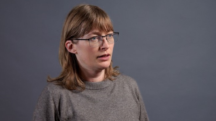 Head and shoulders image of a person wearing glasses and a grey polo neck jumper