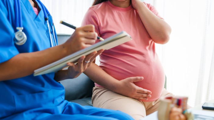 A pregnant woman sat with a clinician at a maternity appointment.