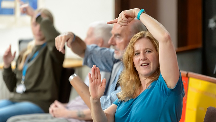 A row of four people sat down doing arm exercises