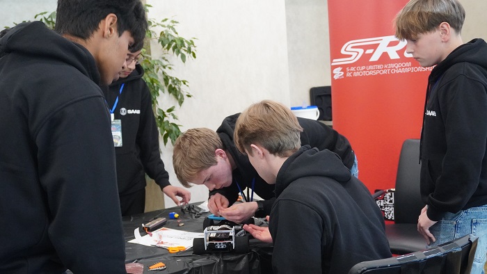 Group of young people looking at and working on a remote controlled car