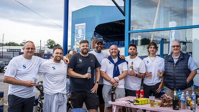 A group of people stood outside with the Sheffield Wednesday football ground in the background