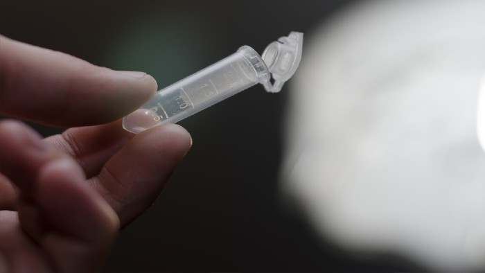 A hand holding a vial of medicine