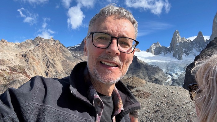 A photo of Steve Pagden, stood on a mountain side smiling at the camera.