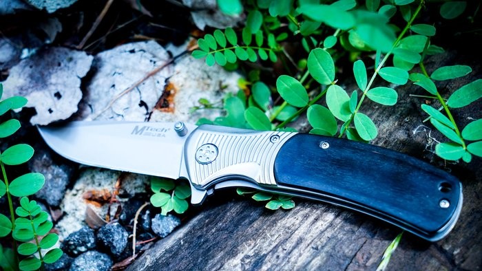An opened flick knife abandoned in a woodland area.