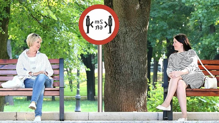 Two women sat on benches 2 metres apart