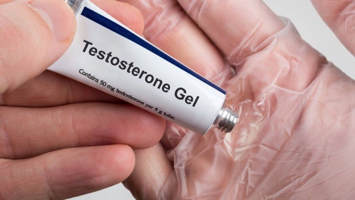 A person squeezing a tube of testosterone gel into their hand