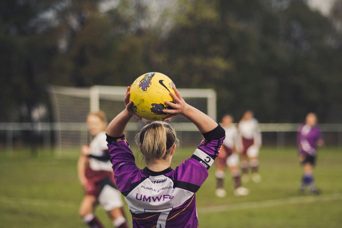 Back of a female footballer holding the ball above her head ready to throw in