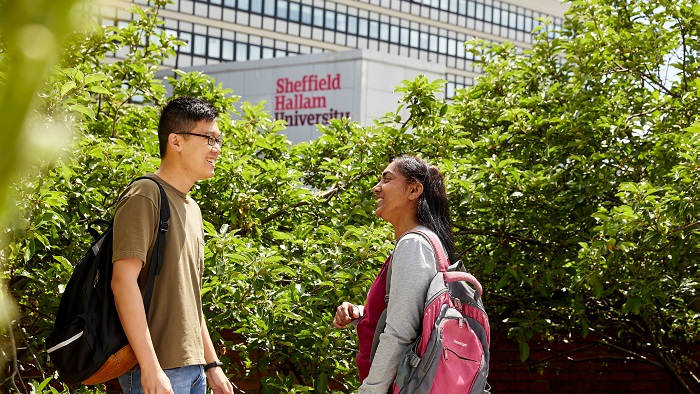 Male and female student talking outside University