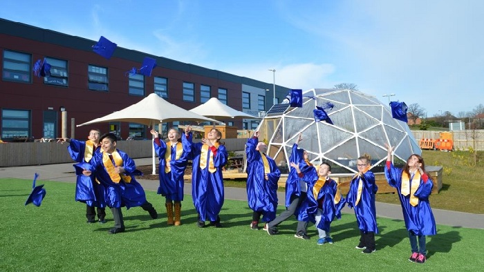 Children in playground in university cap and gowns