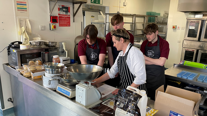 Three pupils in Sheffield Hallam University kitchen with staff member