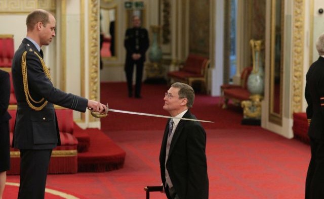 Vice-Chancellor kneeling whilst being knighted by the Prince William