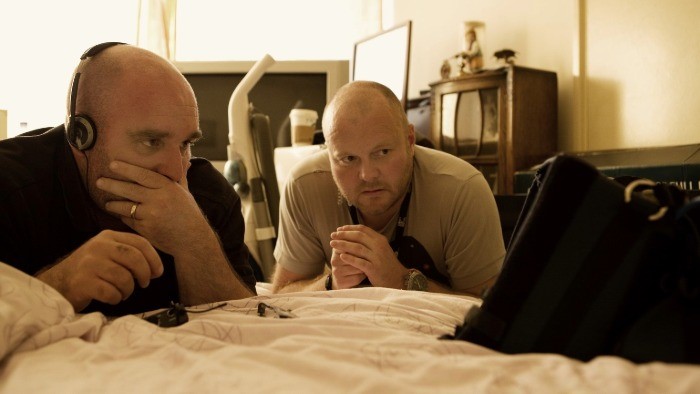Shane Meadows and Mark Herbert sat on set looking at a screen. 