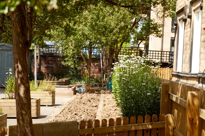 Sunny nursery outdoor area with planters and flowerbeds surrounded by trees and bushes