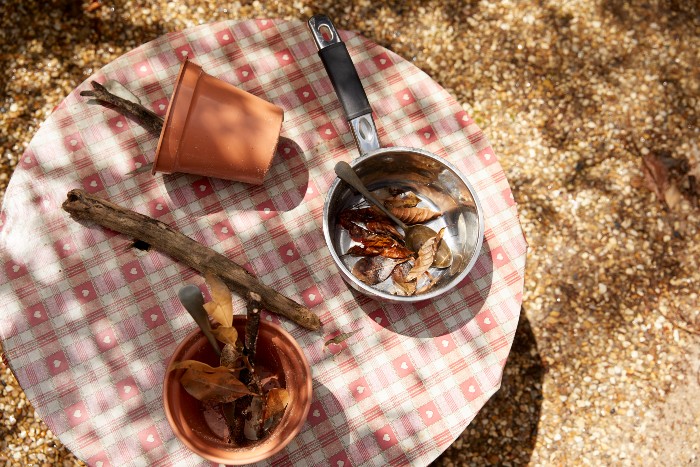 An outdoor activity with pans, terracotta pots and kitchen utensils on a checked table