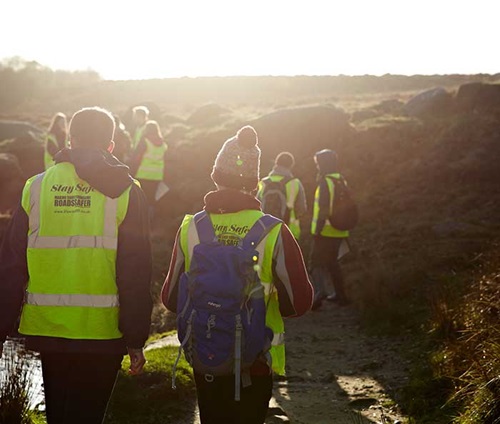 Group of students walking with hi-vis vests on in the Peak District.