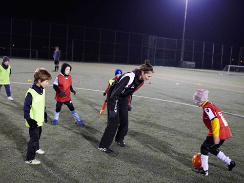 Tutor with children playing football