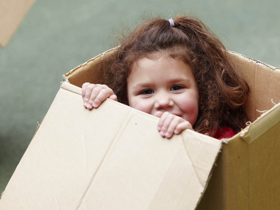 Young girl giggling in cardboard box