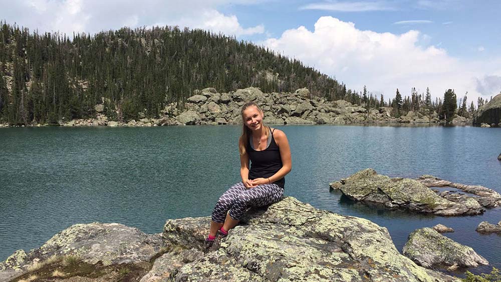 Amy Scott sat on a rock by a lake
