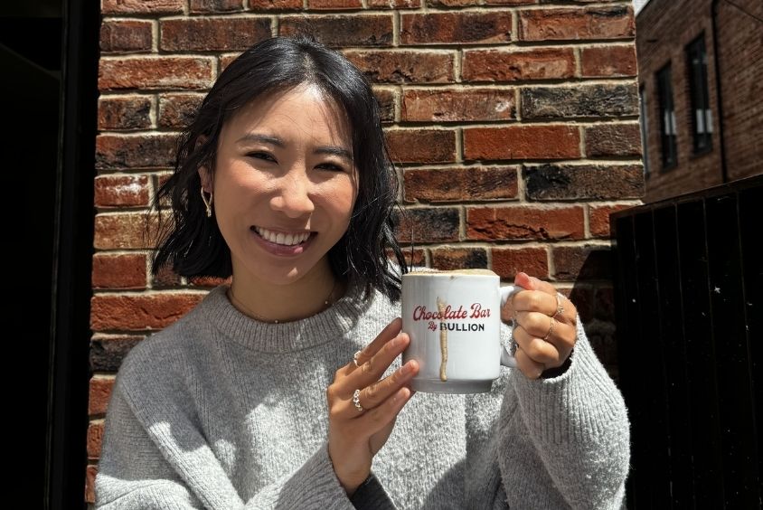 Women smiling holding up a cup of hot chocolate