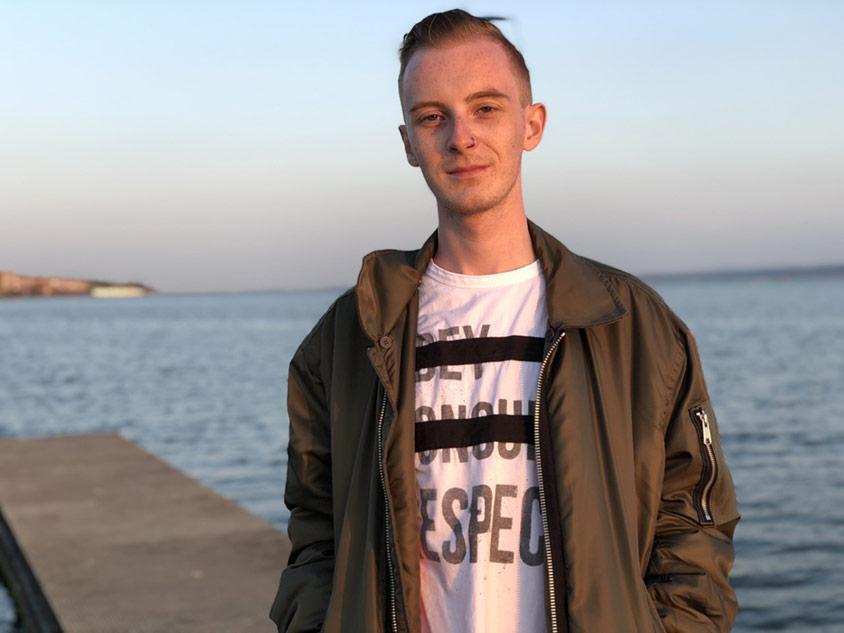Daniel Bird stood by the sea during a sunset posing for a photo