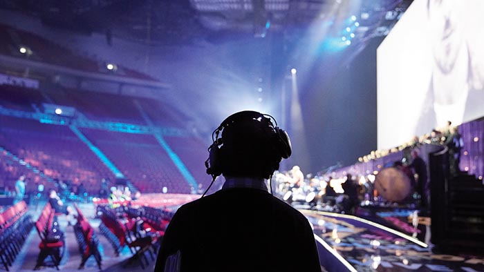 A student wearing headphones in an arena before an event