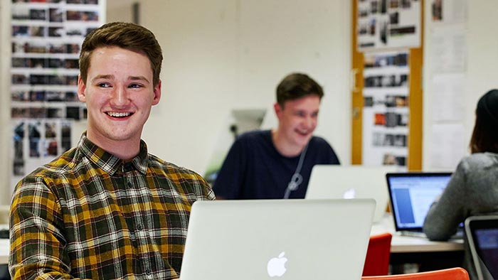 A smiling student working on a laptop