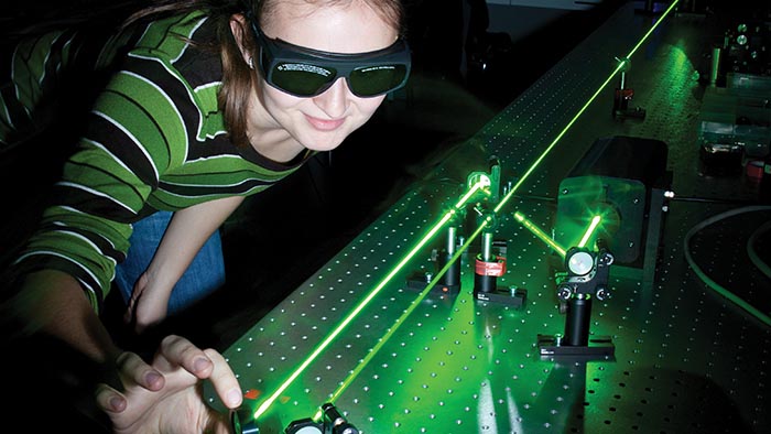 A student wearing goggles working with precision lasers