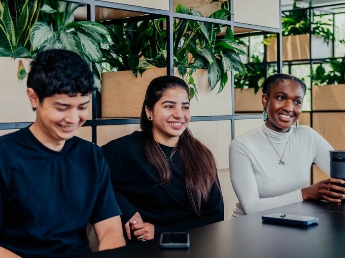 Three students sit in one of Sheffield Hallam's new buildings, relaxed and smiling.