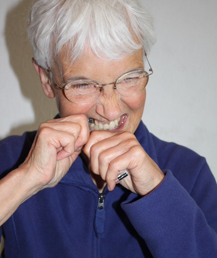 Elderly person biting open a food packet