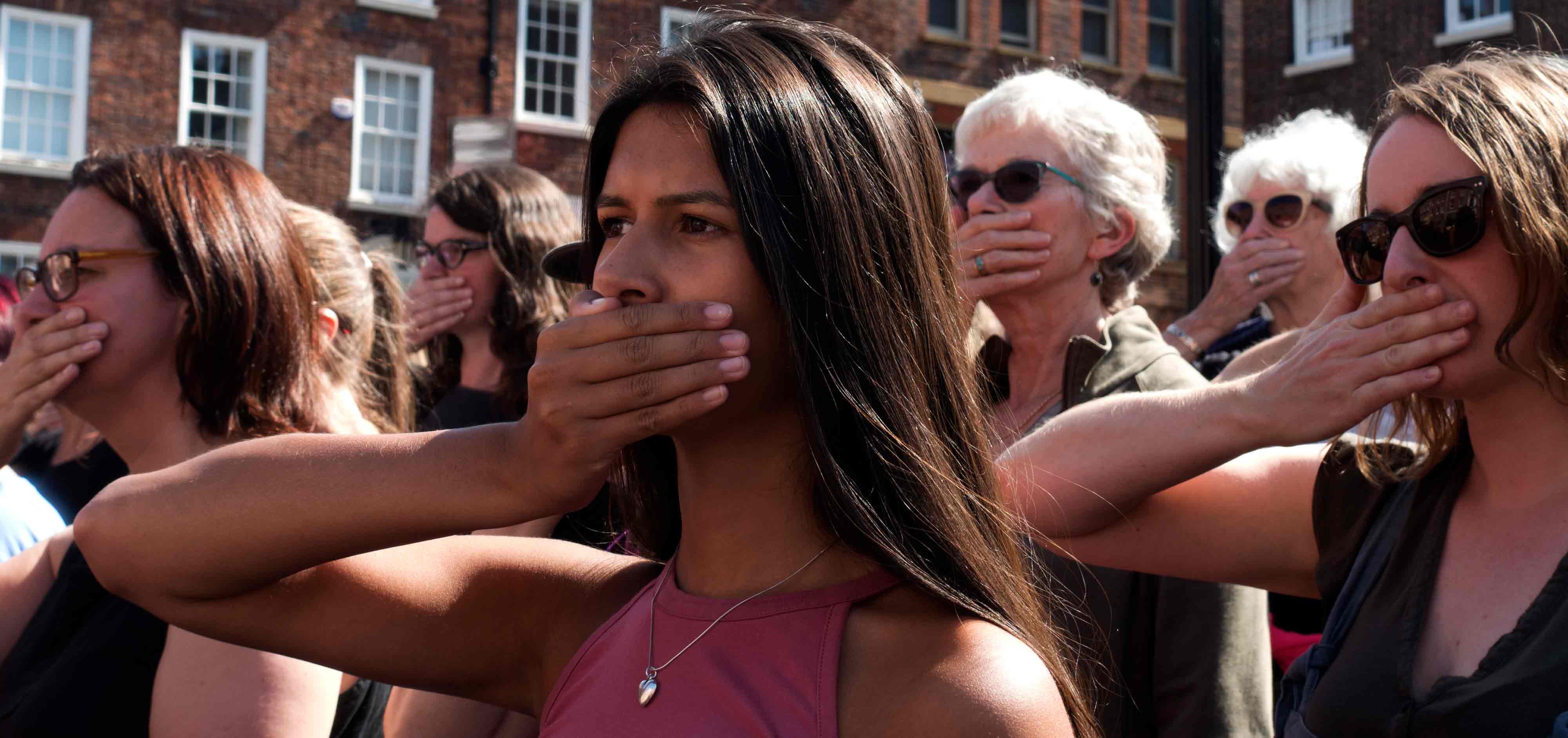 Women hold their hands over their mouths as part of Chloë Brown's 'A Soft Rebellion in Paradise'