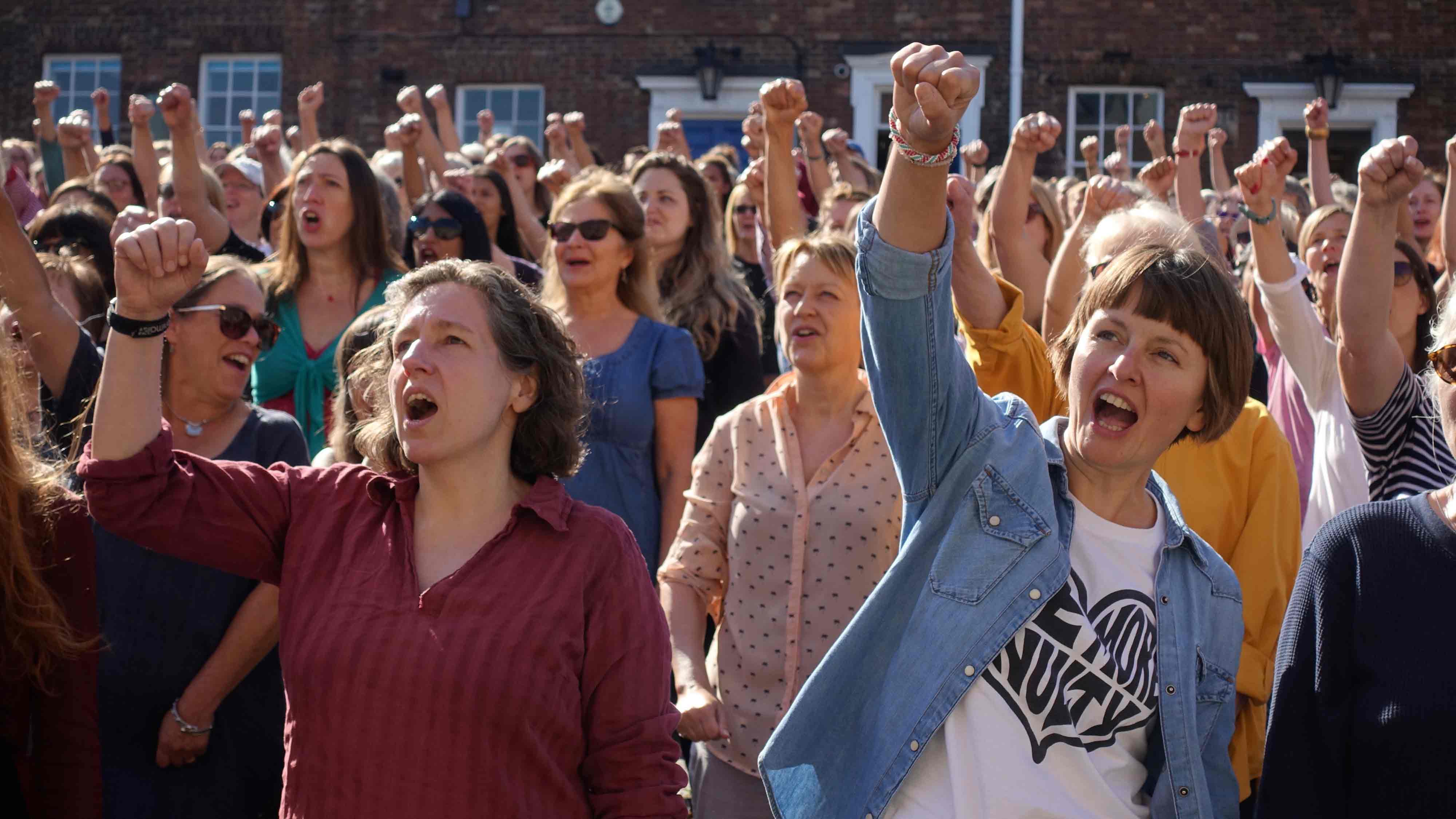 Women hold their fists in the air as part of Chloë Brown's 'A Soft Rebellion in Paradise'