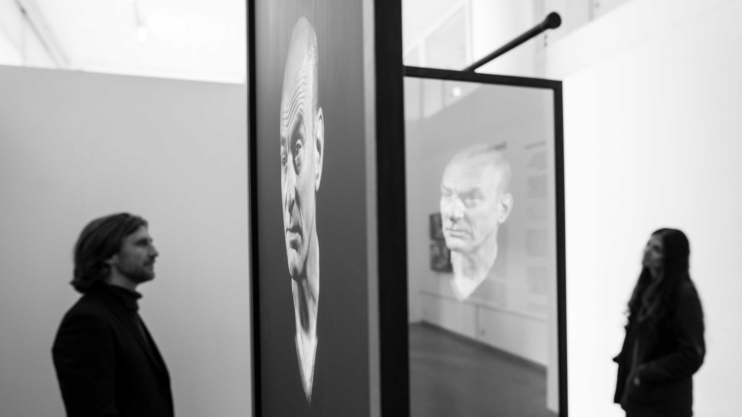 Installation of Mirror I by David Cotterrell - An image of a man is displayed on a screen. David Cotterrell and Ruwanthie de Chickera are viewing the work.