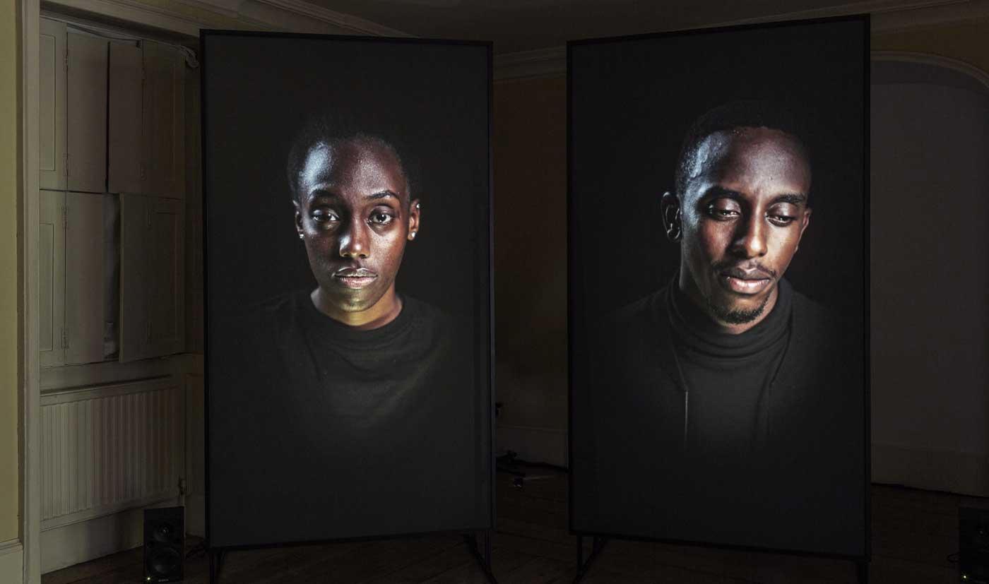 Installation image of Mirror IV by David Cotterrell. A man is shown on a screen twice with different expressions.