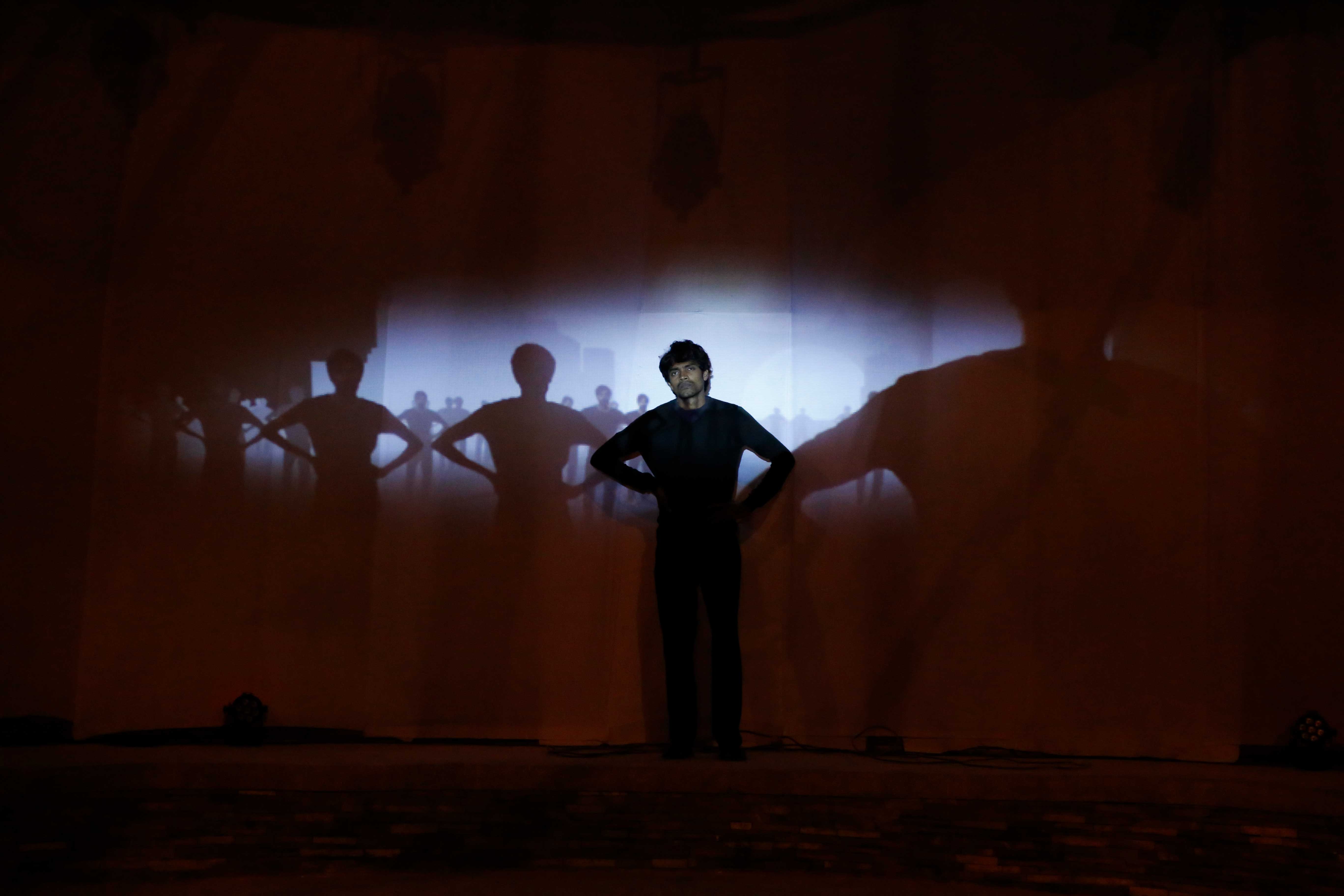 Performance image of Thought Curfew by David Cotterrell. A man stands on a stage.