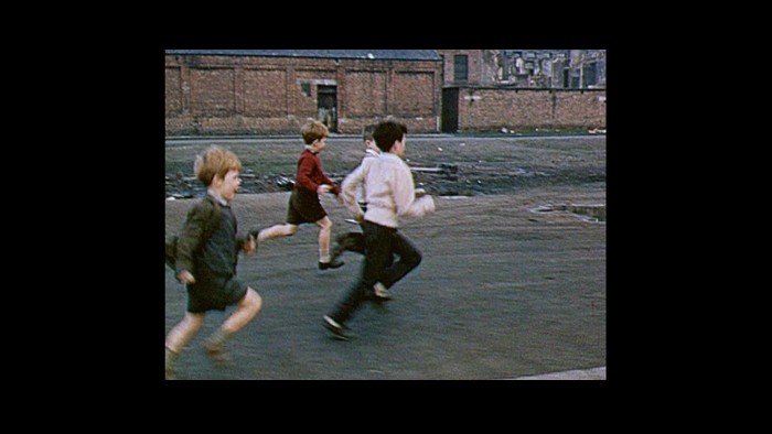 A still from the From Scotland with Love film. A group of schoolchildren run across a playground