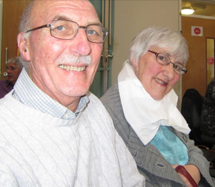 An older couple smiling with one of them wearing a next brace for support