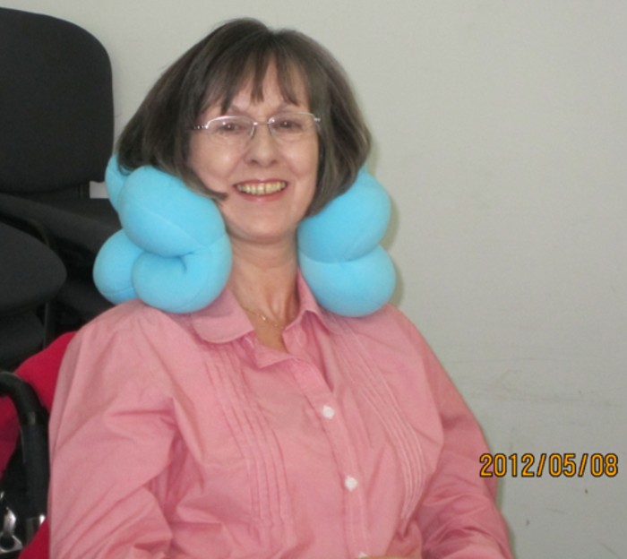 A smiling older woman wearing a padded blue neck brace 