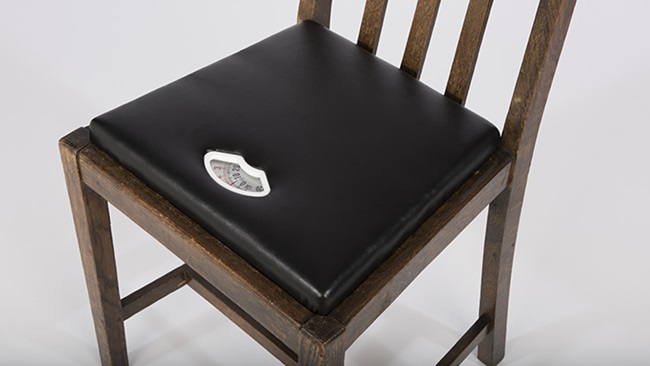 A hybrid chair and weighing scale. An ordinary wooden chair with leather padding. There is a dial embedded in the seat pad to show the weight of the user.
