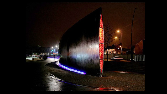 The metalwork water fountain erected outside of the Sheffield Station, light up in red and blue lights at night 