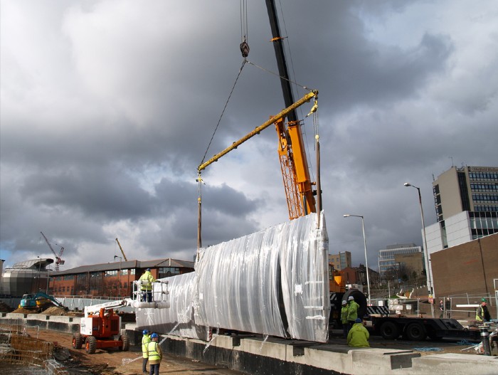 The installation of the metalwork water fountain outside of the Sheffield Station. A crane lowering the metalwork into position.