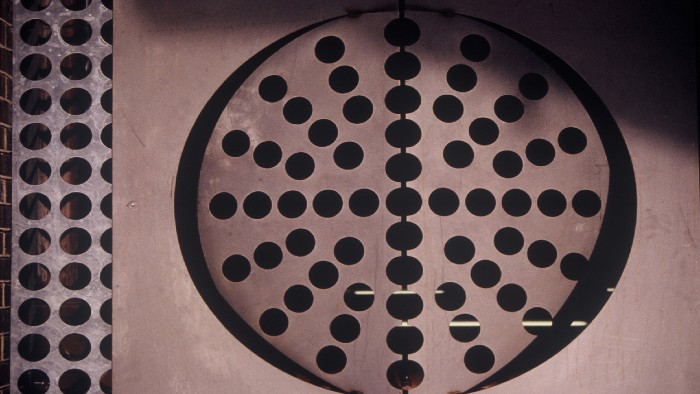 A piece of metalwork on the side of a Sheffield City Centre building. A rectangular piece of metal with hole arranged to make a circular shape in the middle