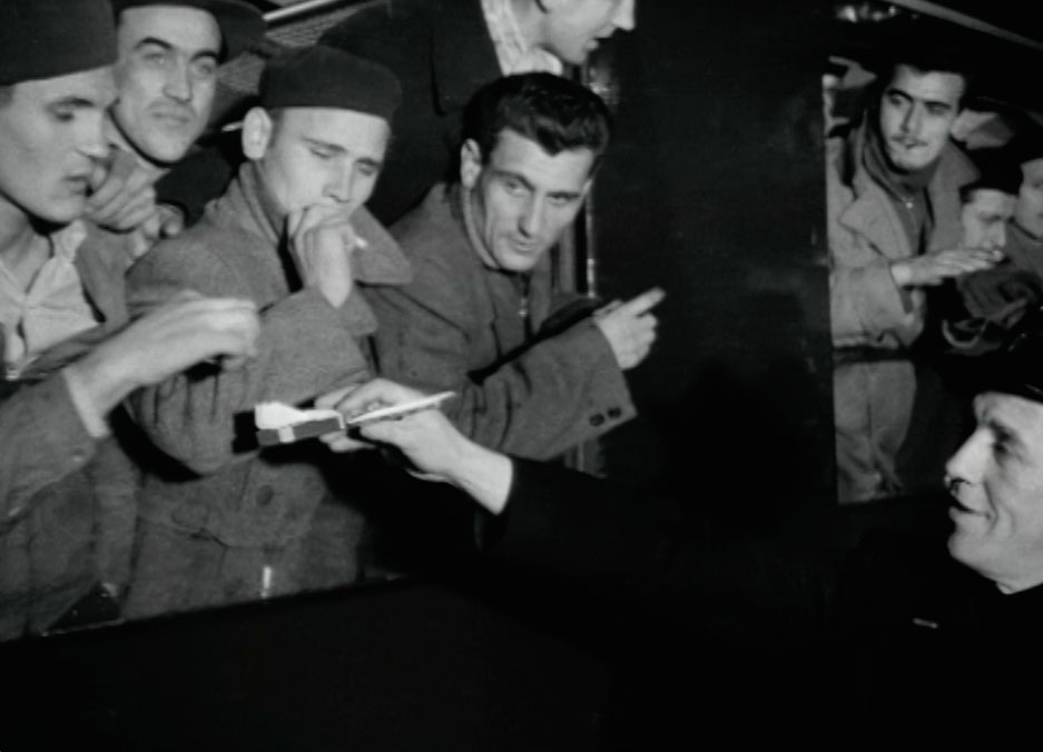 Still from Virginia Heath's 'We Are All Migrants' showing migrants being welcomes and offered cigarettes