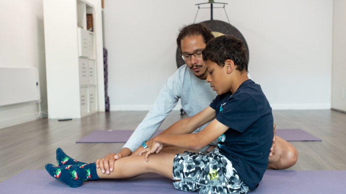 A physiotherapist working with a child on a mat