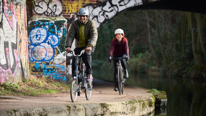 A man and woman riding bikes by a canal