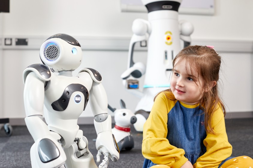 A young girl sat with a robot