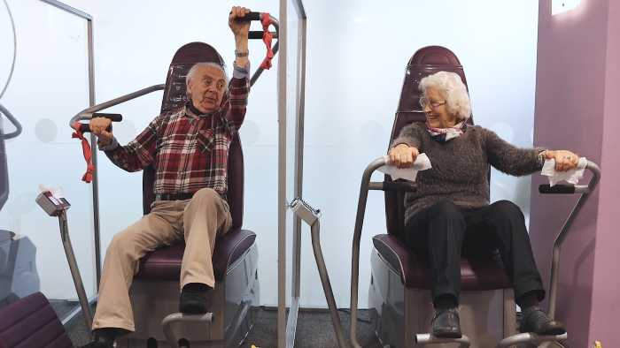 Older man and woman using power assisted exercise equipment
