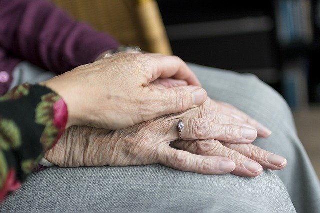A younger person holding an elderly person's hand