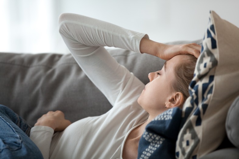 Woman lying on sofa feeling fatigued