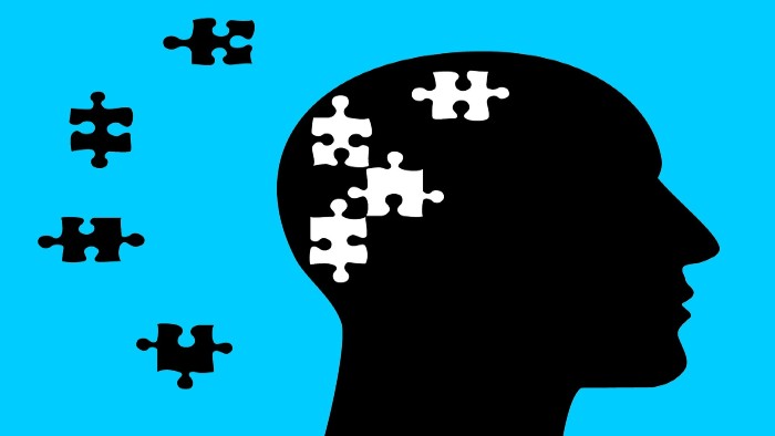 A black silhouette of a head and neck with white jigsaw pieces missing. The black jigsaw pieces are spread on the left. The whole image has a blue background  
